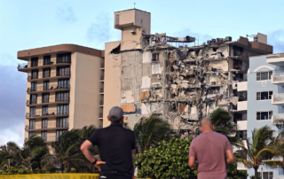 Two men observe the damage to Champlain Towers South condominium, which collapsed on June 24, 2021