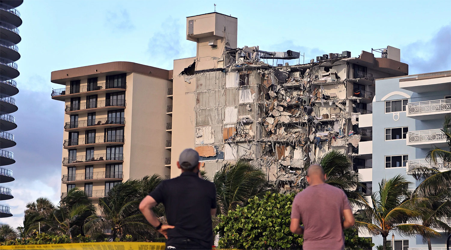 Two men observe the damage to Champlain Towers South condominium, which collapsed on June 24, 2021