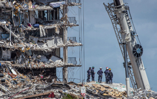 A team of emergency crews look on atop a mound of rubble from the Surfside, FL condominium collapse