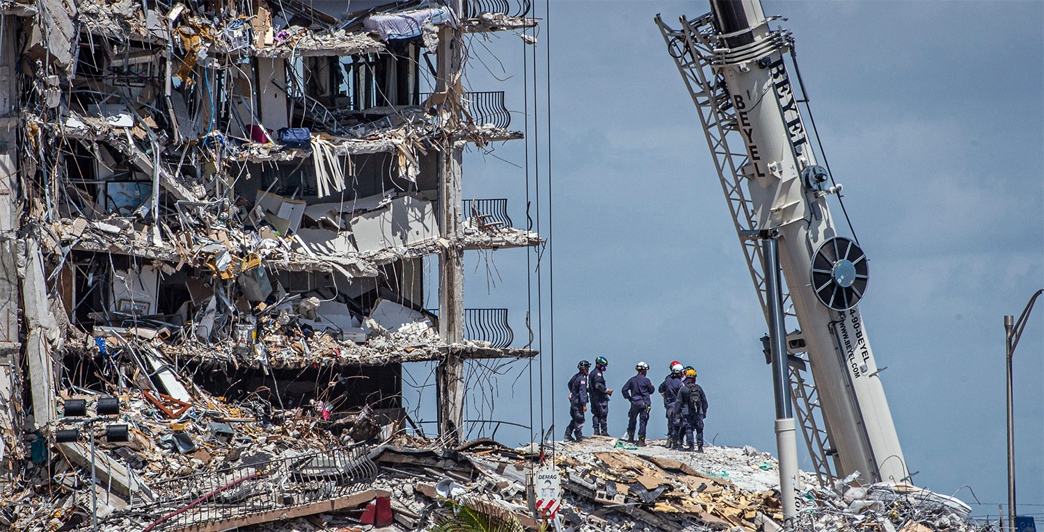 A team of emergency crews look on atop a mound of rubble from the Surfside, FL condominium collapse