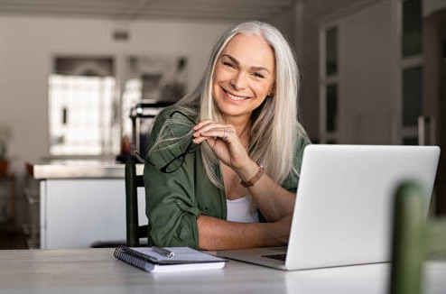 Woman smiling at computer after completing her building inspection signup through Building Mavens