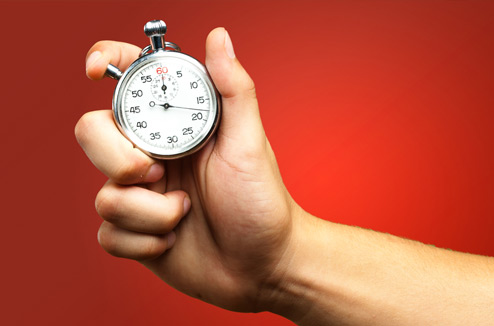 Hand holds stopwatch against a red background