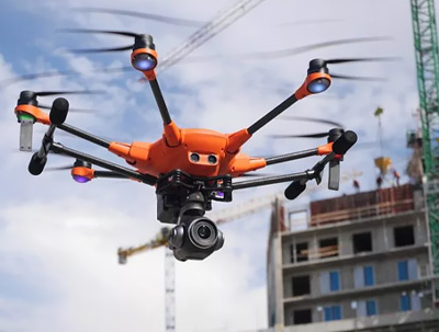 Orange drone flies above a condo under construction.