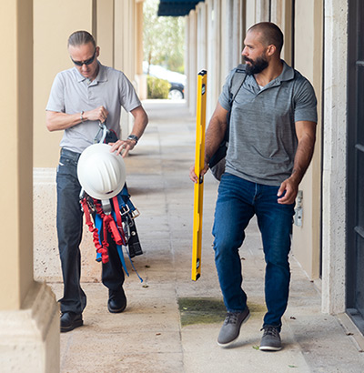 Building Mavens team walks outside at an inspection site, holding equipment.