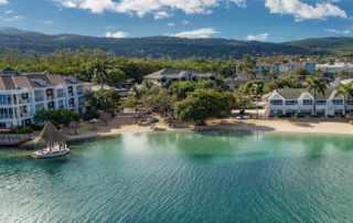 Aerial view of Sandals, Montego Bay over the ocean looking back at a chain of hotels.