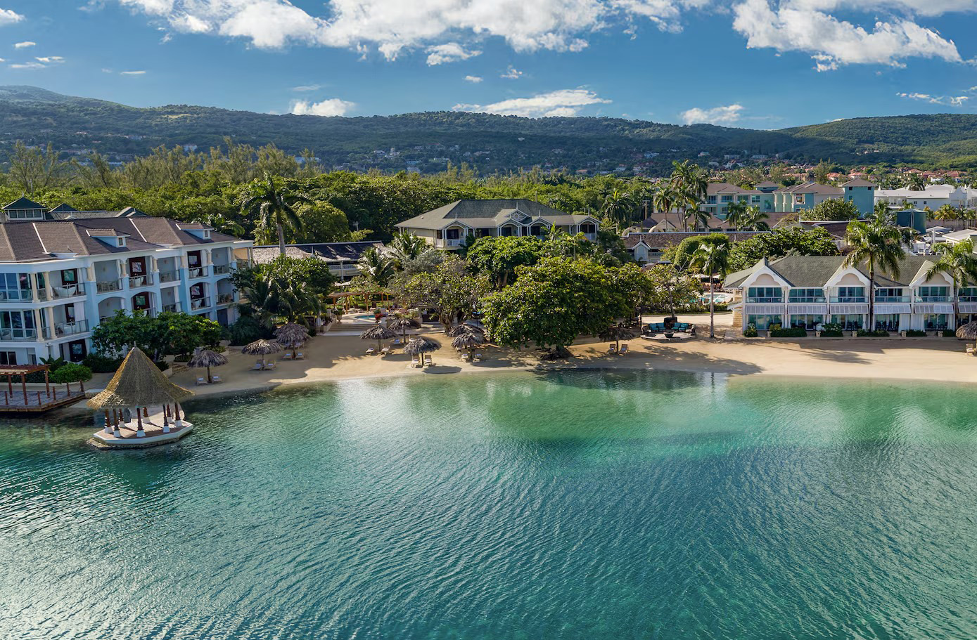 Aerial view of Sandals, Montego Bay over the ocean looking back at a chain of hotels.