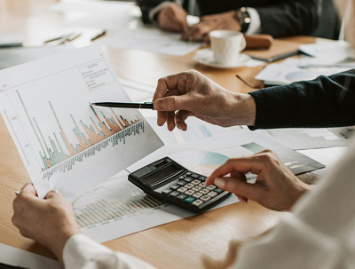 People in a boardroom good over a set of bar graphs on a sheet of paper.